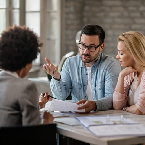 Mid adult couple discussing with financial advisor while analyzing documents on a meeting in the office.